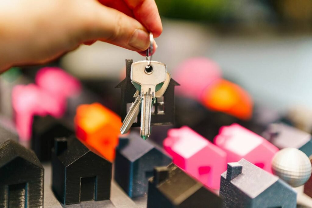 Hand holding house keys over small model homes representing buying a home in Bothell