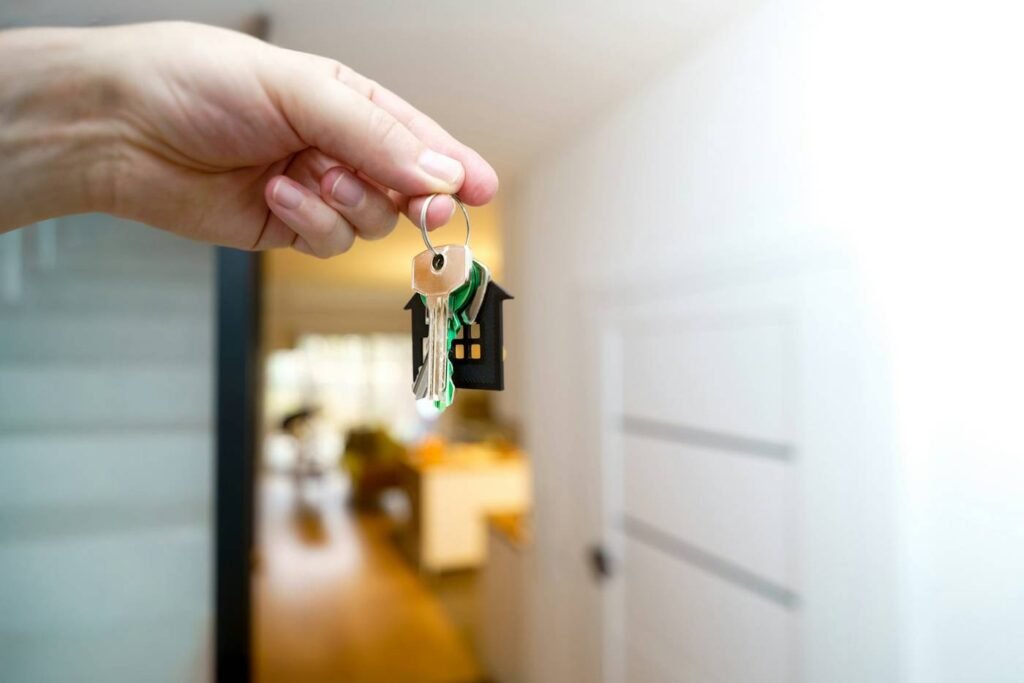 Hand holding house keys at a front door after closing on a home sale