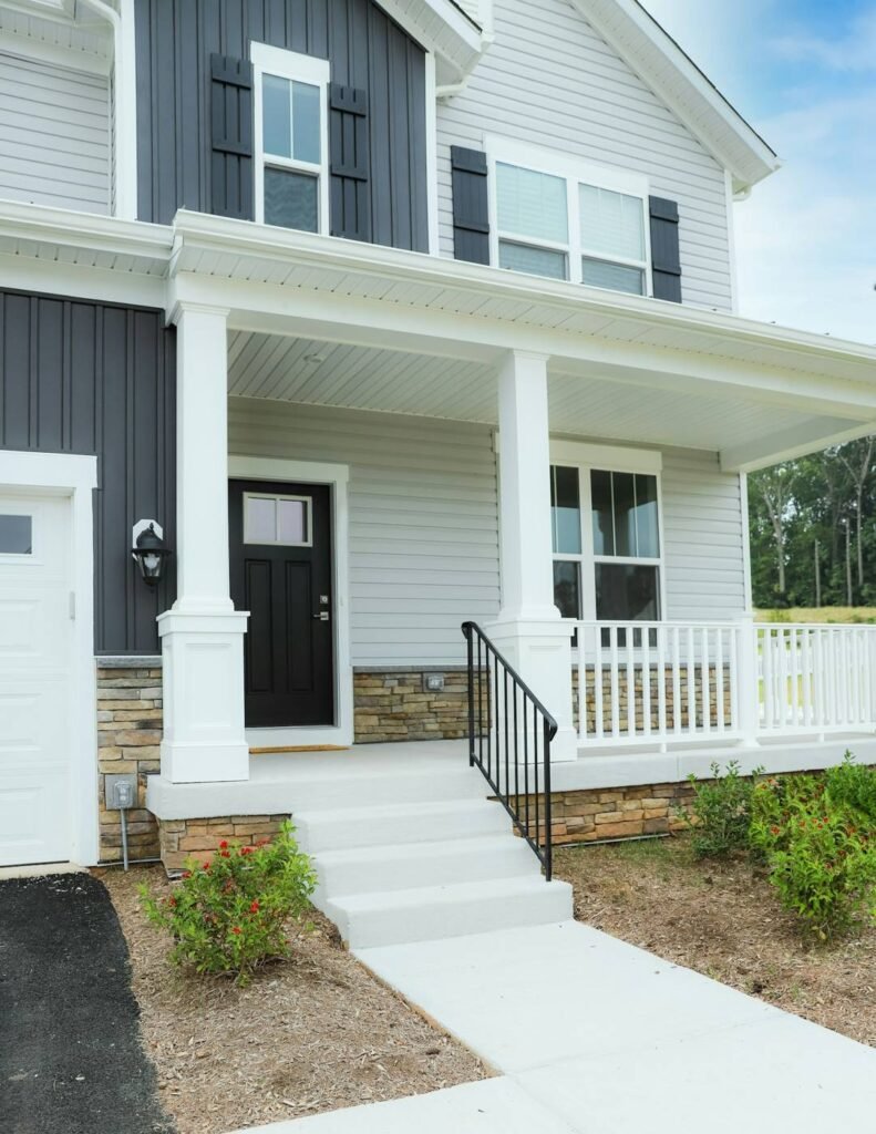 Front porch of a freshly painted white home with black front door showing strong curb appeal